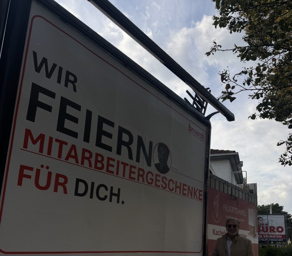 Bernd Bode vor der bmerch Plakatwand „Wir feiern Mitarbeitergeschenke für dich“